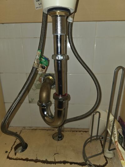 Stainless P-trap rebuild under a residential sink.