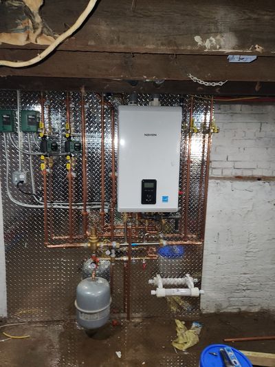 Navien tankless boiler installation with copper manifold on a diamond-plate backing — recent E&GJ work.