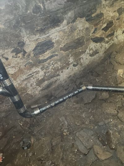 Cast iron sewer line installation against a stone basement wall — typical NYC pre-war repair work by E&GJ.