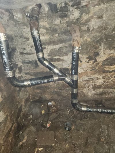 Cast iron sewer line repair against a stone basement wall.